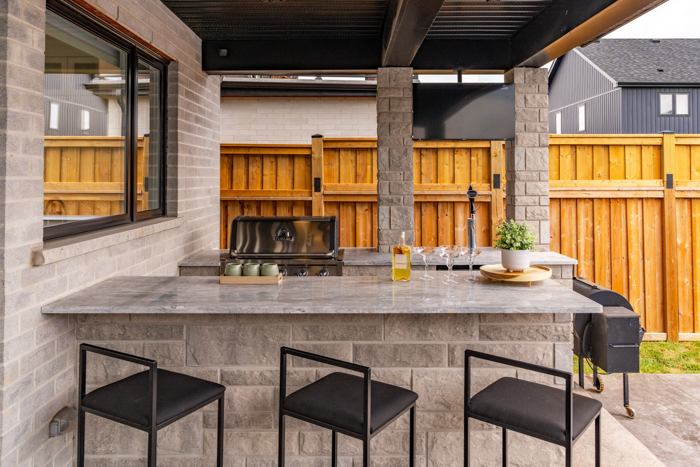 Luxury Stone Outdoor Patio with BBQ – Homes with Style Staging Elegant stone outdoor patio with BBQ, perfect for luxury entertaining, staged for a high-end home experience.